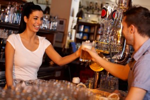 Happy bartender handing glass of bear to customer